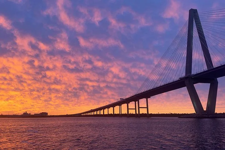 Una vista mozzafiato di un grande ponte sospeso contro un colorato cielo al tramonto.