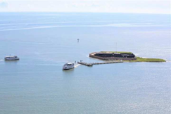 Deux bateaux de passagers naviguent près d'une petite île avec un fort historique.